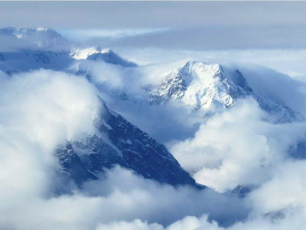 Snow-capped mountains rise above a sea of clouds, showcasing a breathtaking alpine landscape, ideal for nature enthusiasts and adventure seekers.