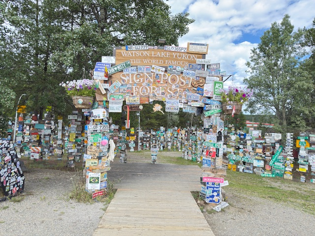 Watson Lake's Sign Post Forest features a colorful archway surrounded by numerous signs, showcasing its unique collection of travelers' markers.